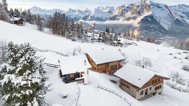A snow-covered mountain village with wooden houses, a ski lift, and a view of distant peaks. - Le Ruisseau by Interhome (Nendaz)