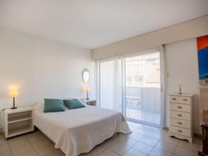 A bedroom with a bed, a nightstand, a dresser, and a window with curtains.