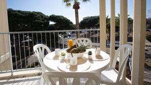 Ein Balkon mit Tisch, gedeckt für zwei Personen, mit einer Obstschale, einer Pflanze und zwei Tassen.