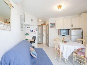 A compact room with a bed, a dining table with chairs, a TV, and a refrigerator. - Les Rives Latines by Interhome (Fréjus)