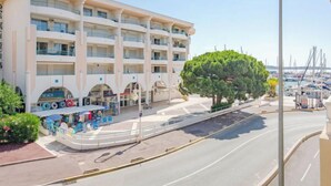 A multi-story hotel with balconies, a covered outdoor seating area, and a view of the marina. - Les Rives Latines by Interhome (Fréjus)