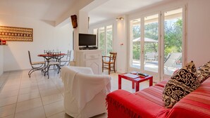 A spacious living area with a dining table, chairs, a sofa, and a TV. - Les Collines de valescure by Interhome (Saint-Raphaël)