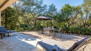 An outdoor patio with lounge chairs, a table, and an umbrella. - Les Collines de valescure by Interhome (Saint-Raphaël)
