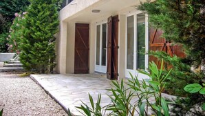 A two-story house with a stone-paved entrance, a wooden door, and a balcony with metal railings. - Les Collines de valescure by Interhome (Saint-Raphaël)