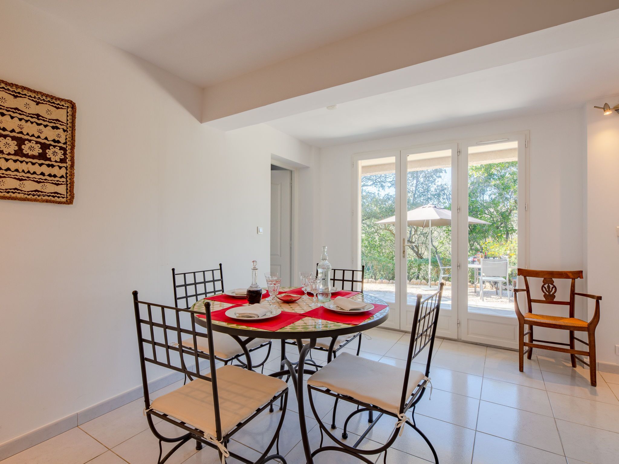 Un coin repas avec une table ronde dressée pour quatre personnes, entourée de chaises, et une porte donnant sur l’extérieur.