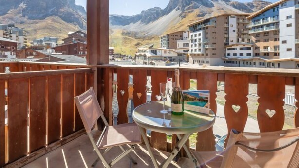 A balcony with a table, chairs, and a bottle of wine. - Chalet Club (Val Claret) by Interhome (Tignes)