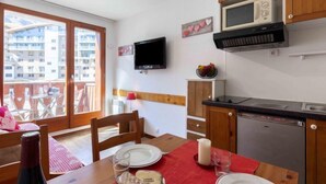 A compact kitchen with wooden cabinets, a microwave, and a TV. - Chalet Club (Val Claret) by Interhome (Tignes)