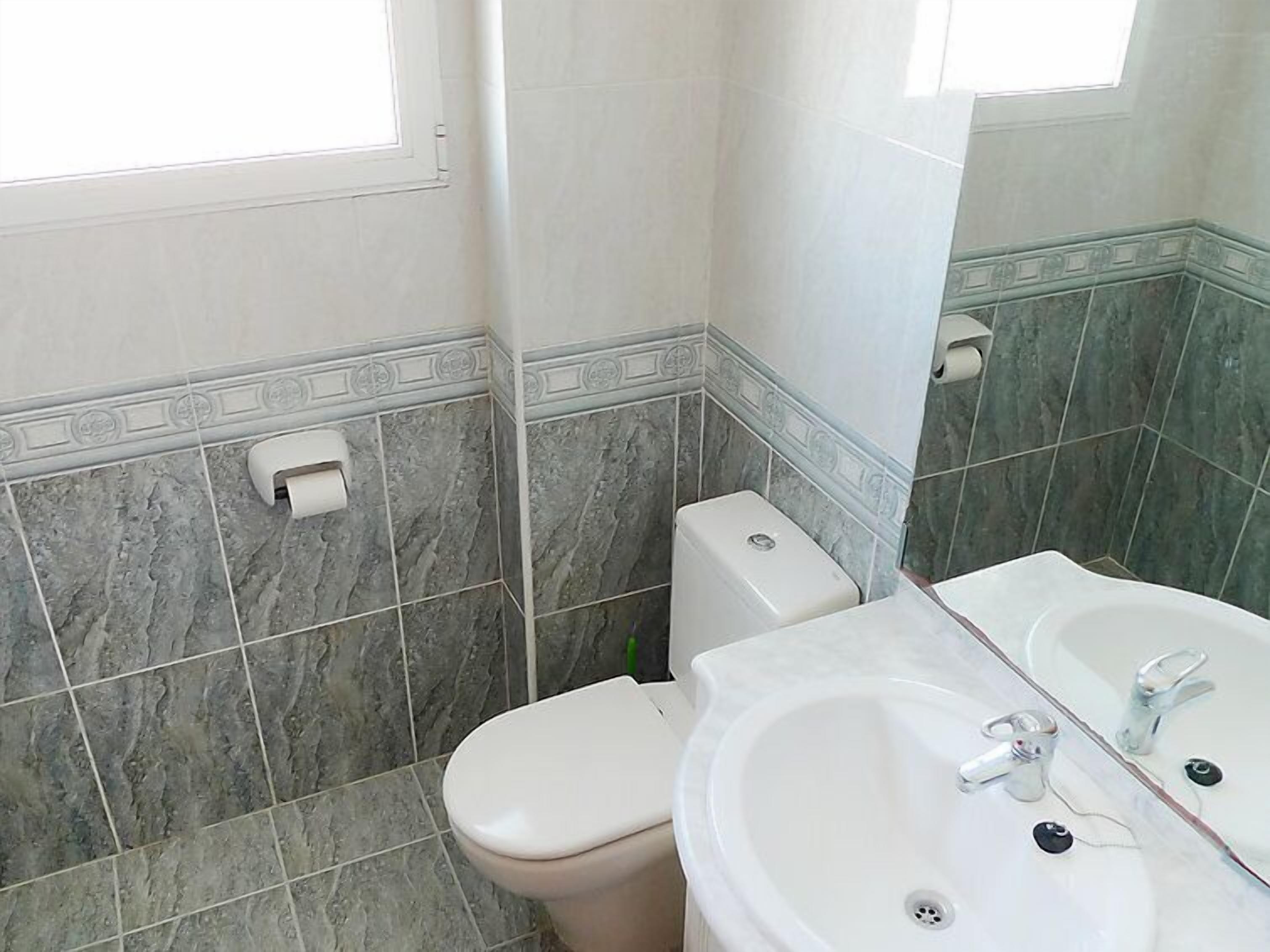 A bathroom with a toilet, sink, and mirror.