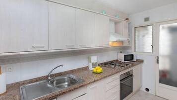 Een koelkast, een oven, een vaatwasser, kookgerei, borden en bestek