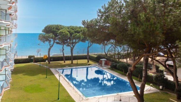 A swimming pool with a view of the sea, surrounded by trees and a well-maintained lawn. - Olivier by Interhome (Blanes)