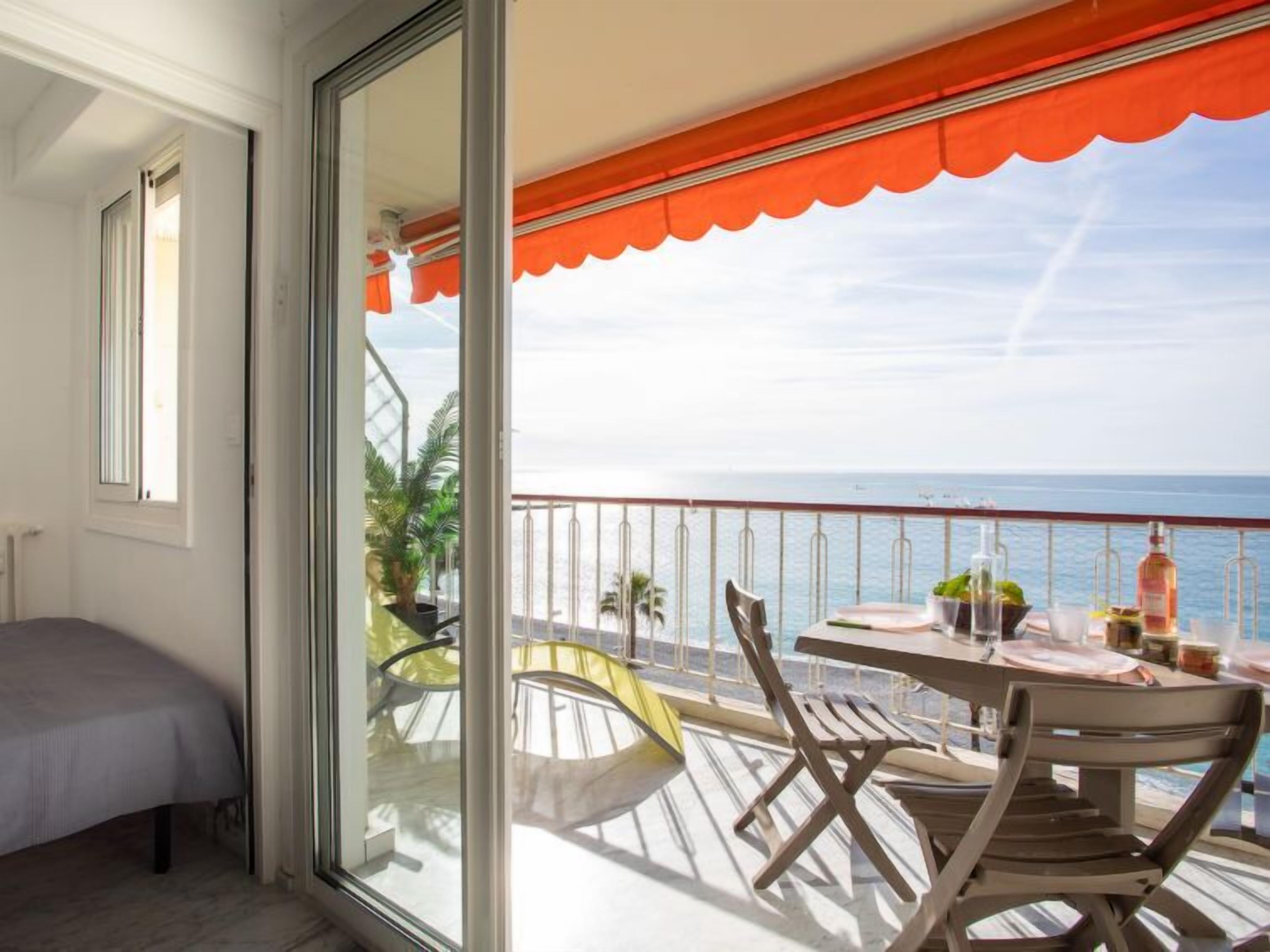 Een balkon met een eettafel, met uitzicht op een waterpartij.
