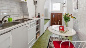 A compact kitchen with white appliances, a sink, and a small dining area with a table and chairs. - Casa Eduardo Apt.1 by Interhome (Ronco sopra Ascona)