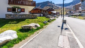 A street with traditional wooden houses, a stone wall, and a clear view of mountains in the background. - Chalet Club (Val Claret) by Interhome (Tignes)
