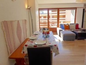 Un coin repas avec une table dressée pour deux personnes, un canapé et un banc.