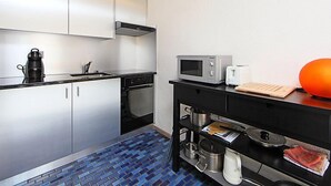 Een moderne keuken met witte kasten, een zwart aanrecht, een magnetron, een broodrooster en een koffiezetapparaat.