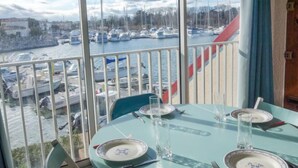 Mesa de jantar posta para dois, com vista para uma marina e barcos.