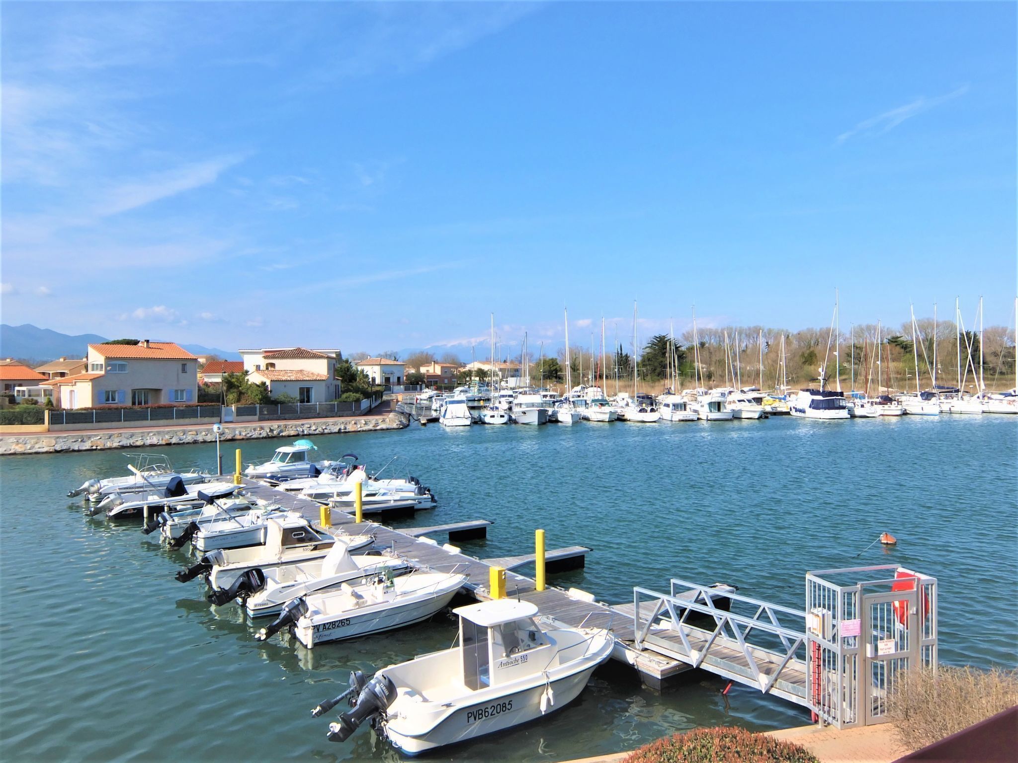 Un puerto deportivo con varias embarcaciones amarradas, un flotador salvavidas y una caseta de salvavidas.