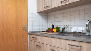 Una cucina con mobili in legno, schienale piastrellato, un piano di lavoro con diversi oggetti e un lavello.