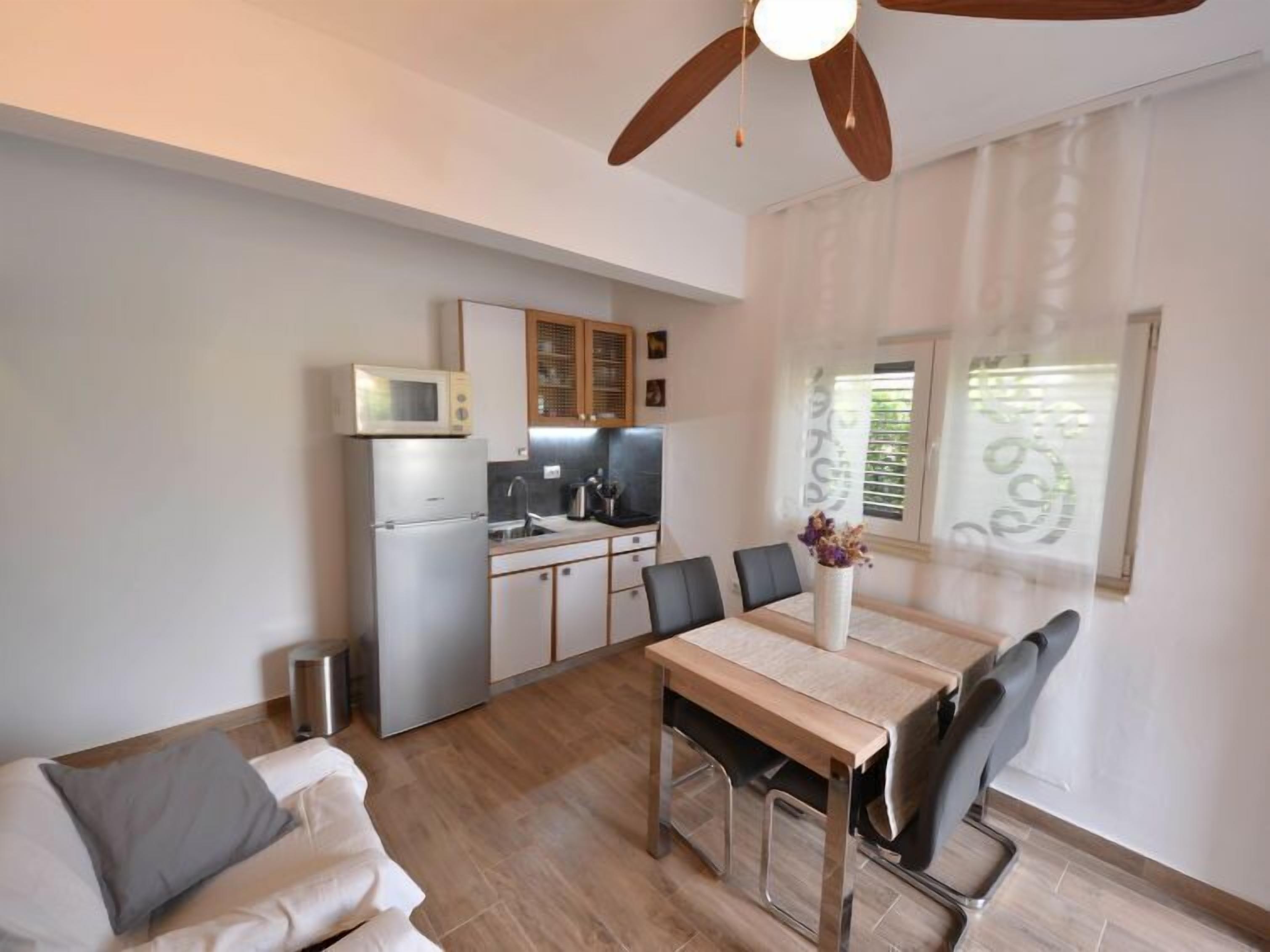 Un espace de vie compact comprenant un coin repas, une kitchenette et un ventilateur de plafond.
