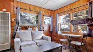 A cozy cabin interior with a sofa, a small table, and two chairs. - Juniper #105 (Big Bear Lake)