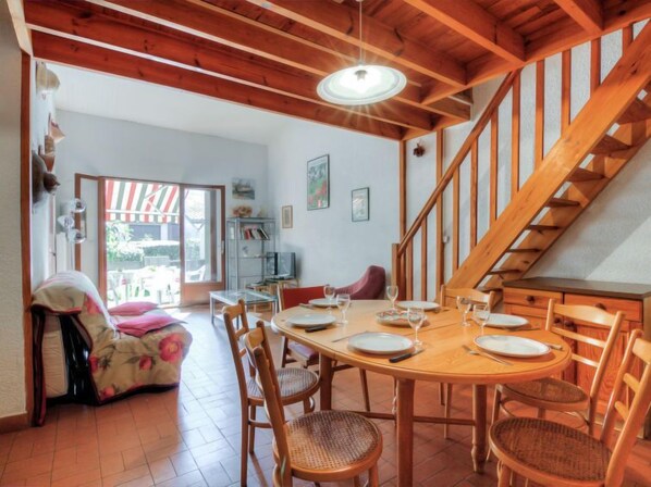 A dining area with a wooden table and chairs, a staircase, and a view of the outside.