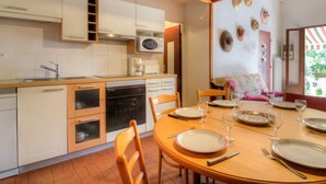 Une cuisine dotée de meubles en bois, d’un four à micro-ondes et d’un coin repas avec une table dressée pour quatre personnes.