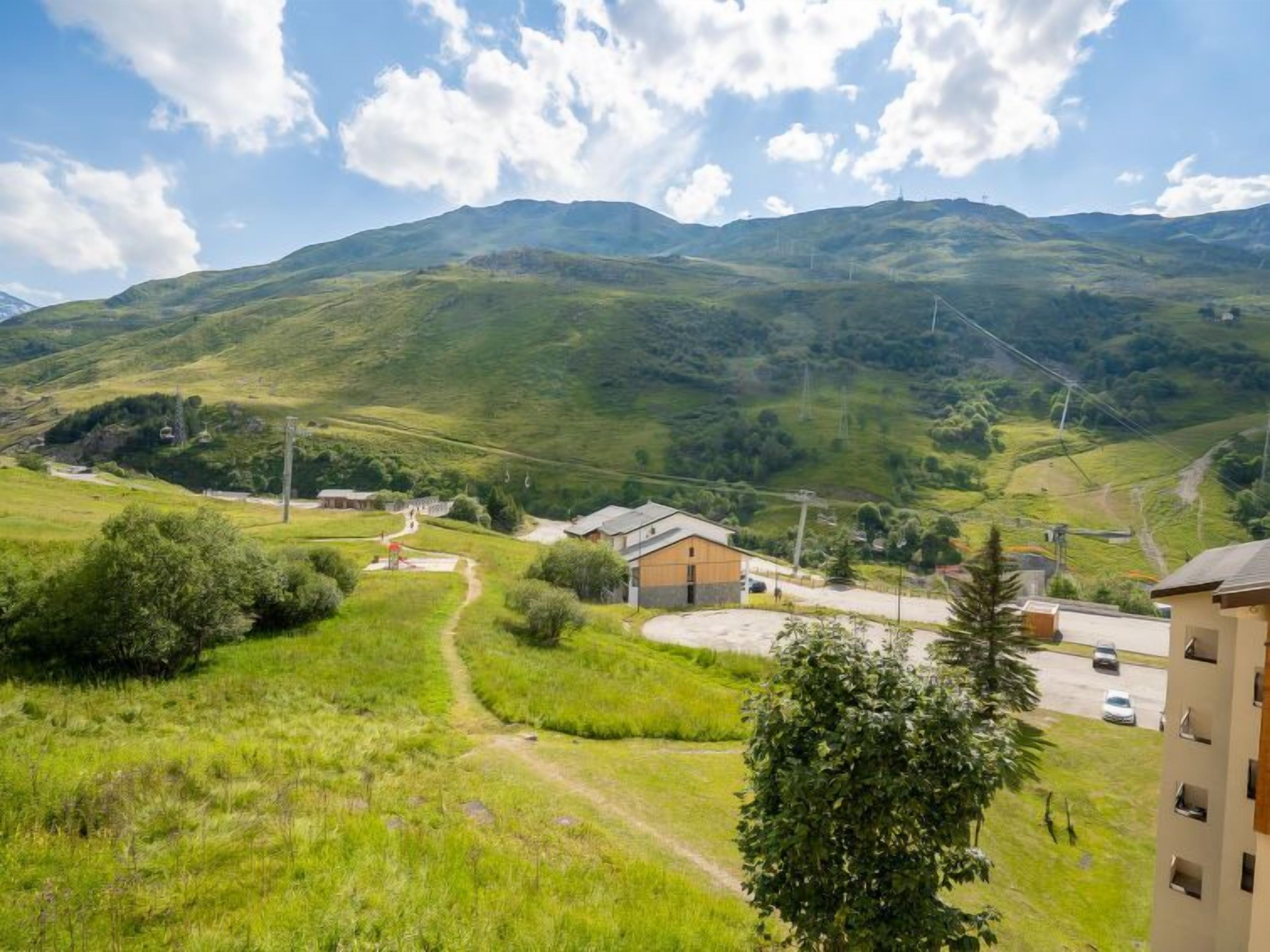 Un paysage rural caractérisé par des collines douces, une route sinueuse et quelques bâtiments.