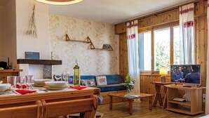 Ein gemütliches Wohnzimmer mit einem Holzespeisetisch, einer Couch und einem Fernseher.