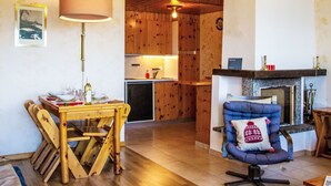 Ein gemütliches Wohnzimmer mit Kamin, Holzmöbeln und einem Essbereich mit Tisch und Stühlen.