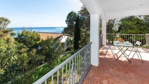 A balcony with a view of the sea, surrounded by greenery and a tiled floor. - Cap de Vol by Interhome (Llançà)