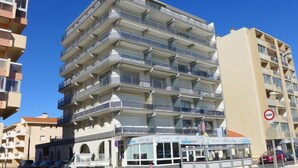 Ein mehrstöckiges Gebäude mit Balkonen, ein Restaurant im Erdgeschoss und ein Verbotsschild in der Nähe.