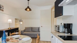 Eine kleine Küche mit Essbereich, einer Couch und einer Kaffeemaschine.