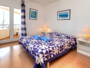 Une chambre à coucher avec un lit, deux lampes de chevet, une fenêtre avec des rideaux et deux tableaux encadrés accrochés au mur.