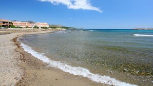 A beach with clear water, a sandy shore, and buildings in the background. - Maritim II by Interhome (Llançà)