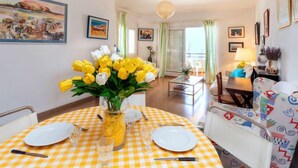 A dining area with a checkered tablecloth, a vase of yellow tulips, and a dining set. - Maritim II by Interhome (Llançà)