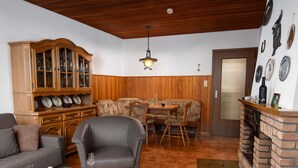 Un salon comprenant un canapé, un fauteuil, une table basse en verre et un coin repas avec une table et des chaises.
