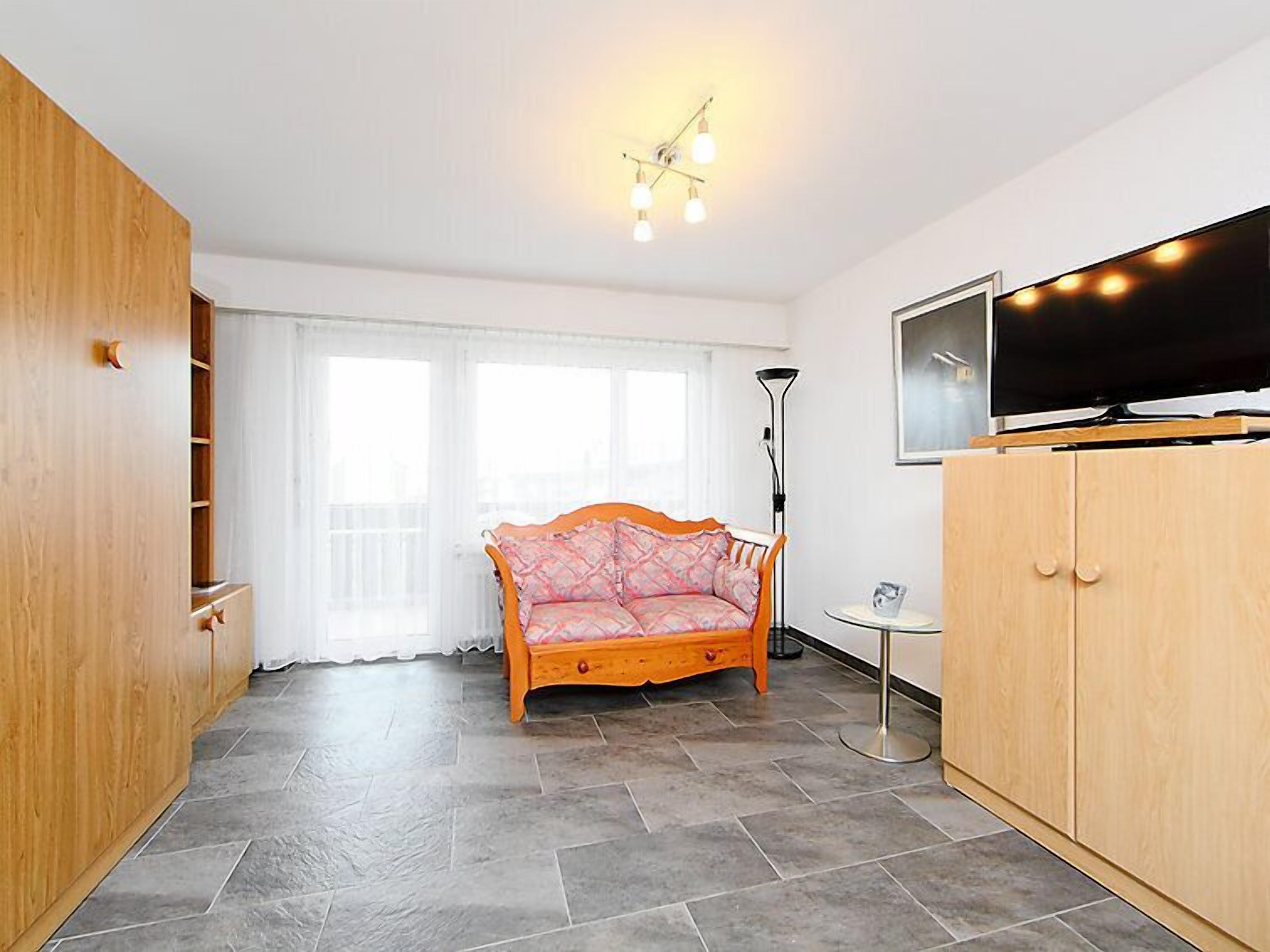 A living room with a sofa, a TV, a floor lamp, and a wardrobe.