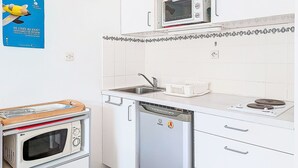 Eine kleine Küche mit Mikrowelle, kleinem Backofen, Geschirrspüler und Spüle.