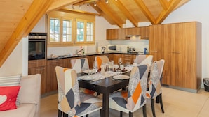 A dining area with a table set for four, surrounded by chairs with patterned upholstery. - Staubbach by Interhome (Lauterbrunnen)
