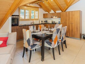 A dining area with a table set for four, surrounded by chairs with patterned upholstery.