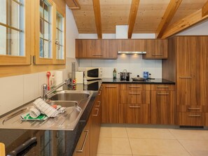 A modern kitchen with wooden cabinets, a stainless steel sink, a microwave, and a stove.
