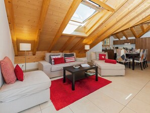 A modern loft with a sloped ceiling, a dining area, and a kitchen.