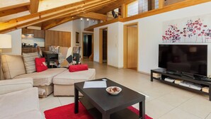 A modern living room with a sectional sofa, a coffee table, and a flat-screen TV. - Staubbach by Interhome (Lauterbrunnen)