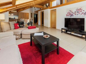 A modern living room with a sectional sofa, a coffee table, and a flat-screen TV.