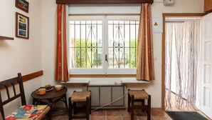 Una habitación con ventana, radiador, puerta y una pequeña mesa con sillas.