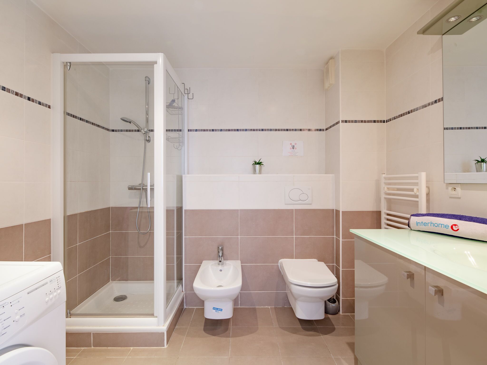 A modern bathroom with a glass-enclosed shower, a bidet, a toilet, and a vanity with a sink.