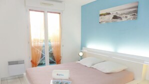 Een slaapkamer met een bed, nachtkastje, wandlamp, raam met gordijnen en een schilderij.