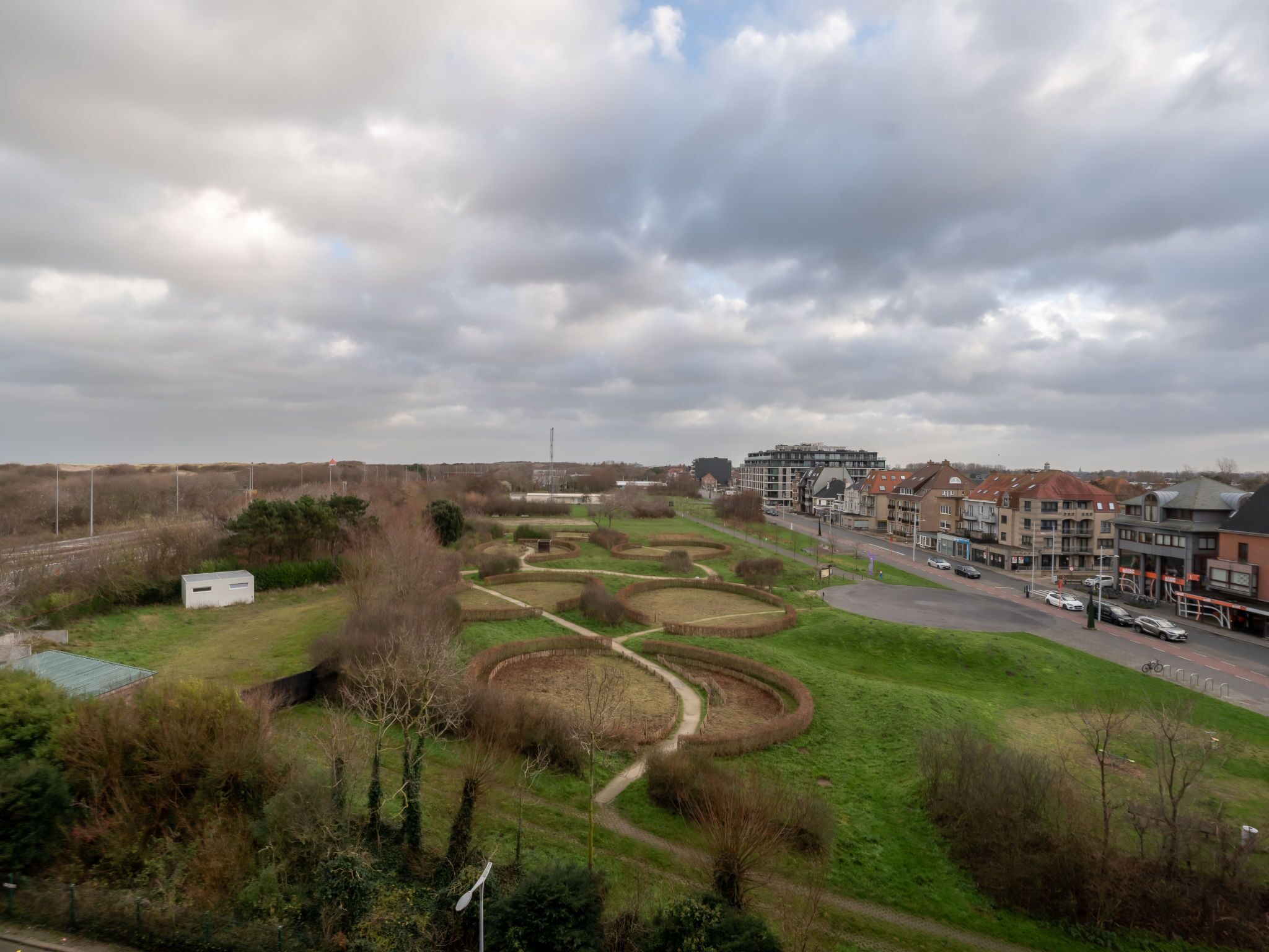 A residential area with a park, a road, and modern buildings.