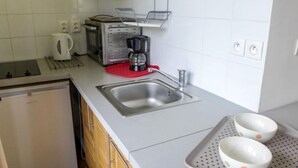 Eine kleine Küche mit Spüle, Toaster, Kaffeemaschine und einem kleinen Kühlschrank.