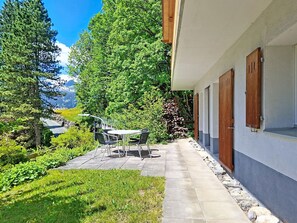 Une terrasse aménagée avec du mobilier d’extérieur, un chemin en pierre et une vue sur un paysage montagneux.